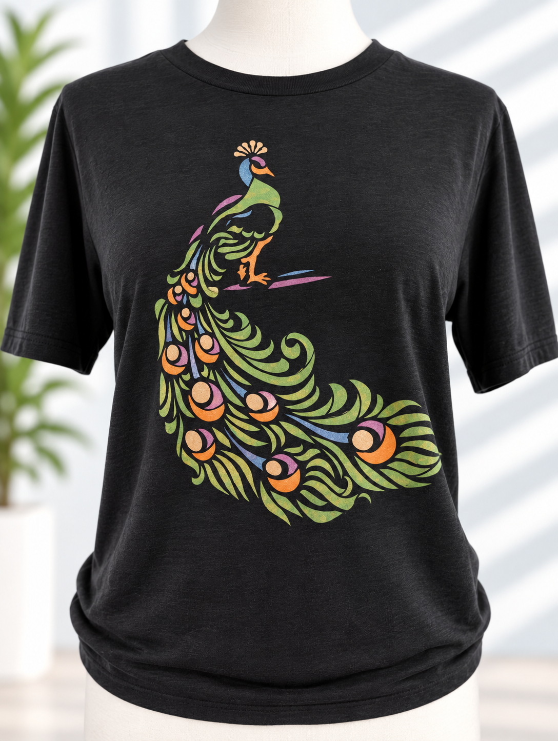 Black t-shirt with colorful hand-painted peacock stencil design in green, orange, and purple