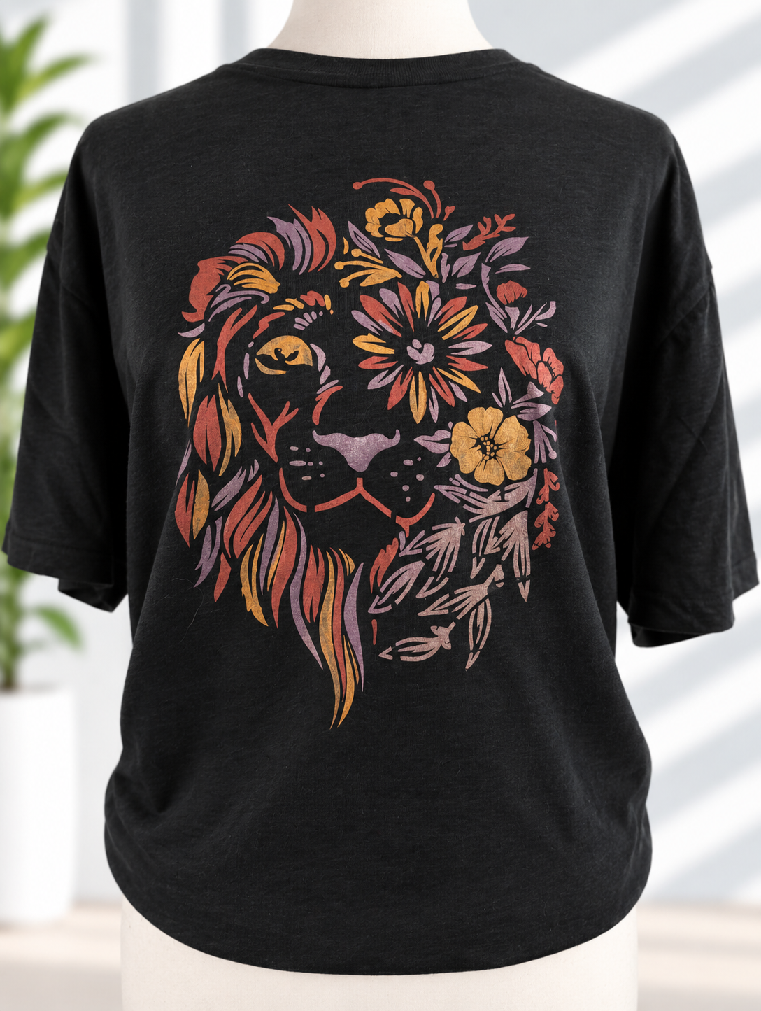 Black t-shirt with hand-painted floral lion design in warm copper, gold, and purple tones